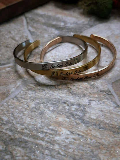 Stack of Bookish Babe bracelets on a stone background. 