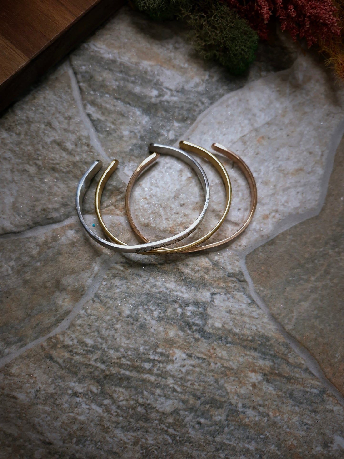 Side view of a stack of Bookish Babe bracelets on a stone background. 