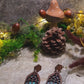 video close up of cathedral window earrings on a stone background surrounded by foliage.