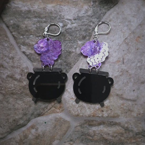 video f Cauldron earrings on a stone and wood background surrounded by foliage 
