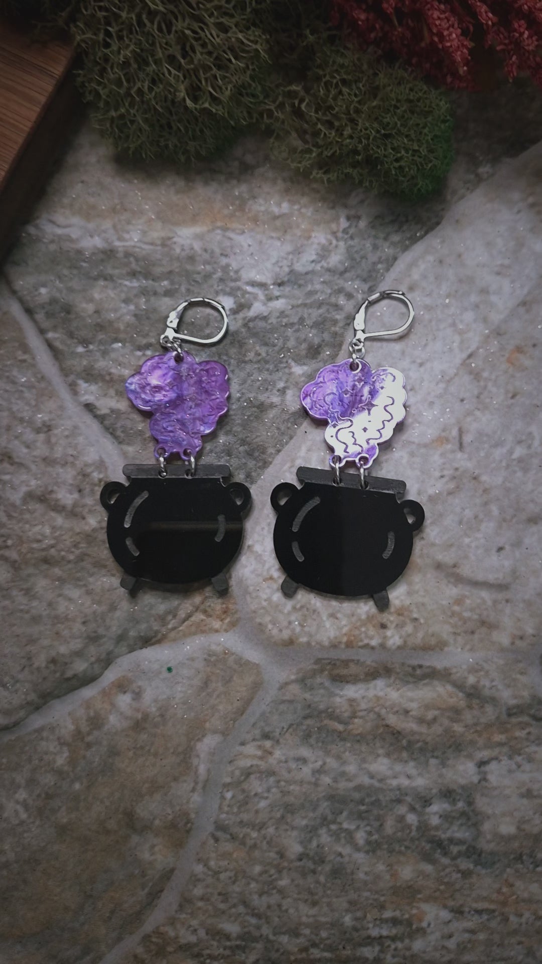 video f Cauldron earrings on a stone and wood background surrounded by foliage 

