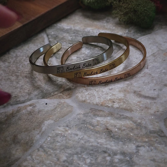 video of Stack of bookish babe  bracelets on a stone background. 