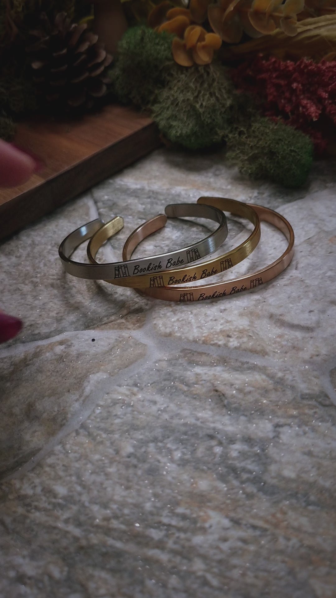 video of Stack of bookish babe  bracelets on a stone background. 