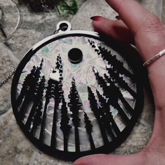 video of forest suncatcher on a stone background surrounded by foliage 
