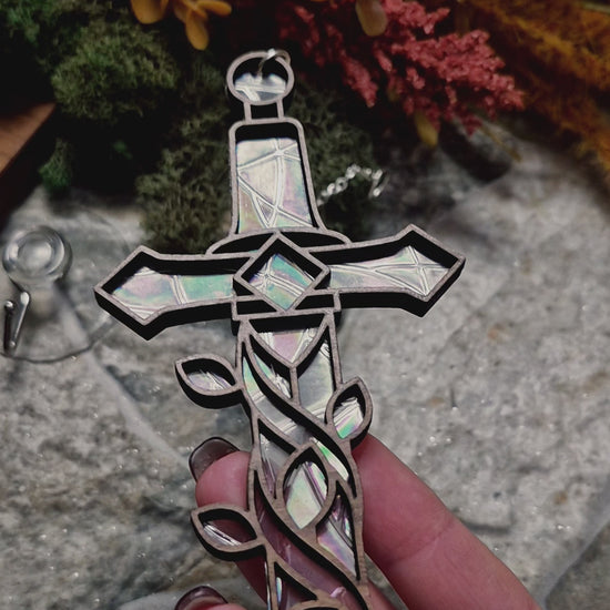 video of Enchanted sword suncatcher on a stone background surrounded by foliage 
