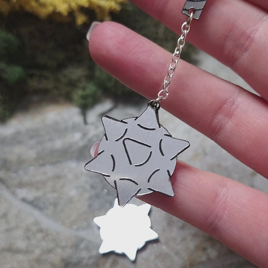 video of flail earrings on a stone background surrounded by foliage. 