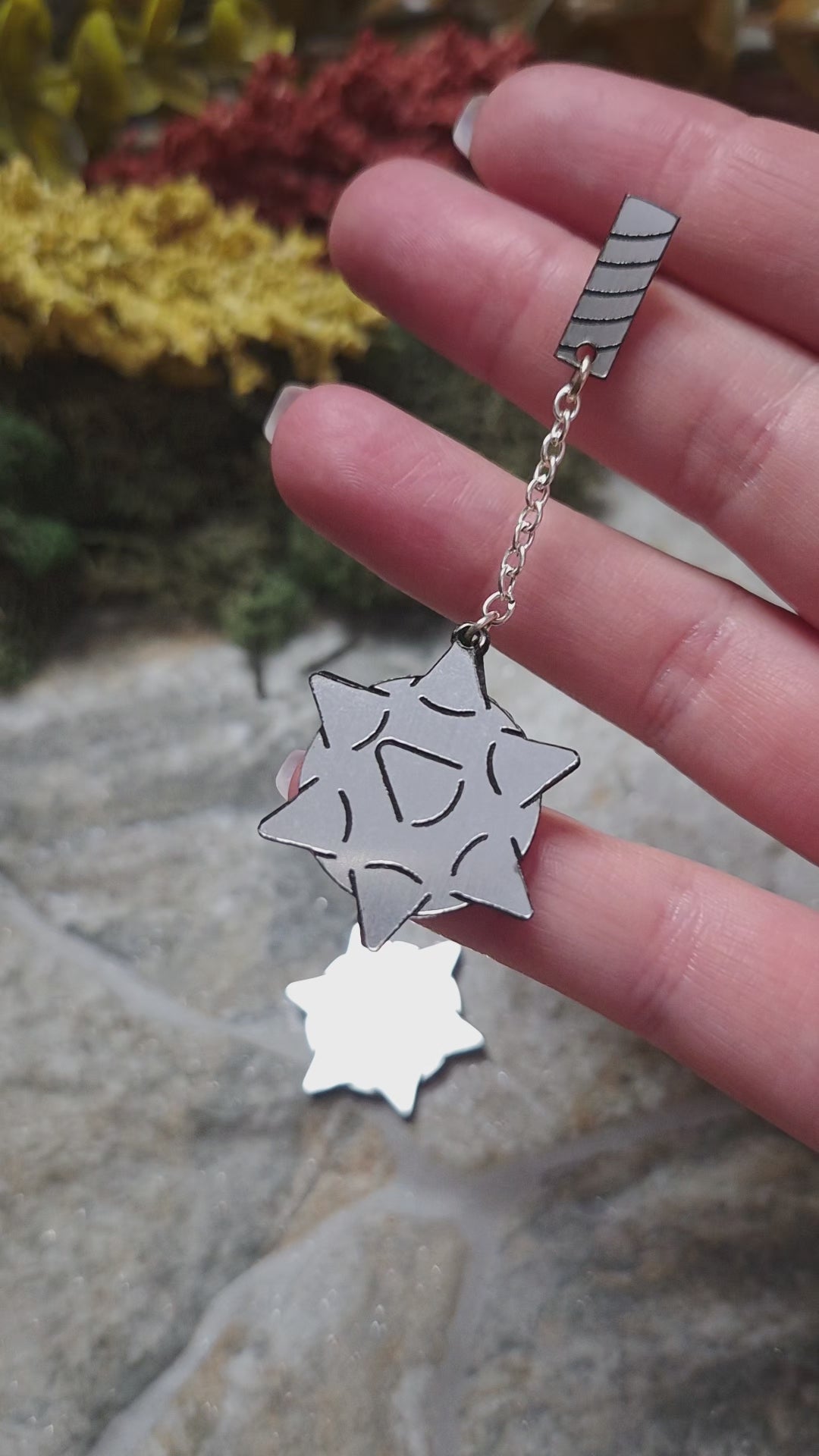 video of flail earrings on a stone background surrounded by foliage. 
