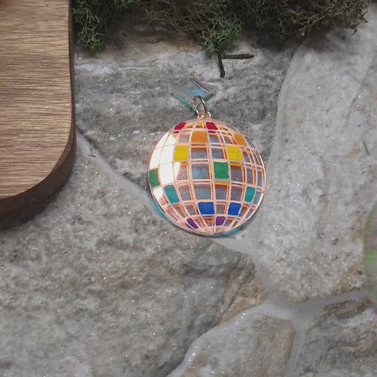 video of rainbow disco ball earrings on a stone background 