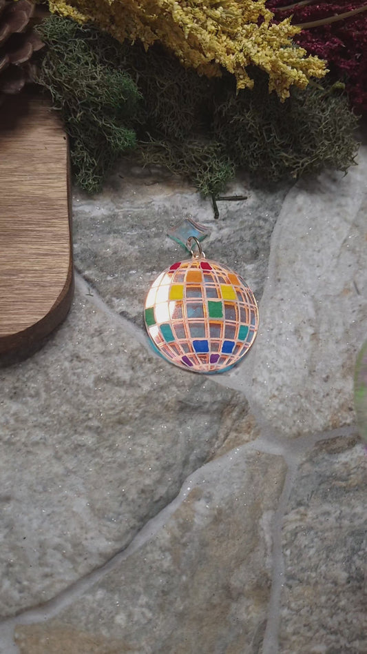 video of rainbow disco ball earrings on a stone background 