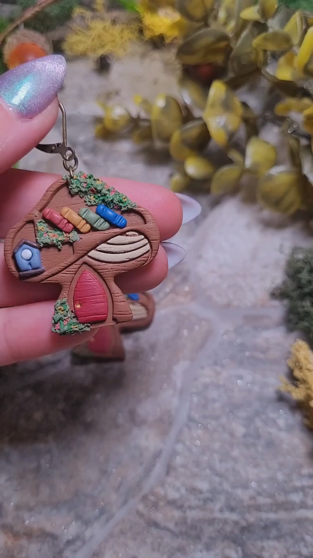 video close up of Mushroom Shelf Earring on a stone background surrounded by foliage. 