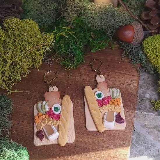 video close up of charcuterie board earrings on a wood background. 