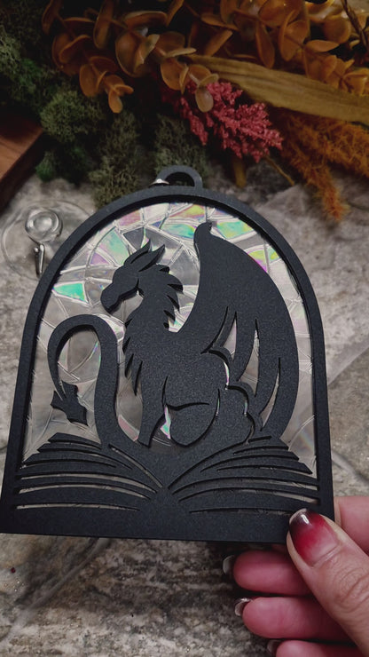 video of Book Dragon suncatcher on a stone background surrounded by foliage

