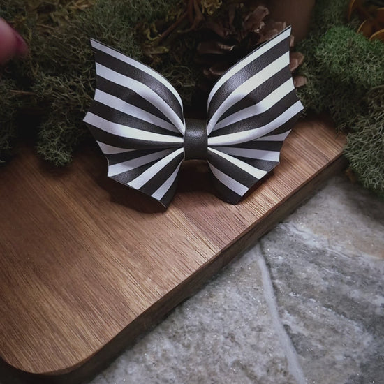 video of Beetlejuice stripe bat bow on a wood and stone background 