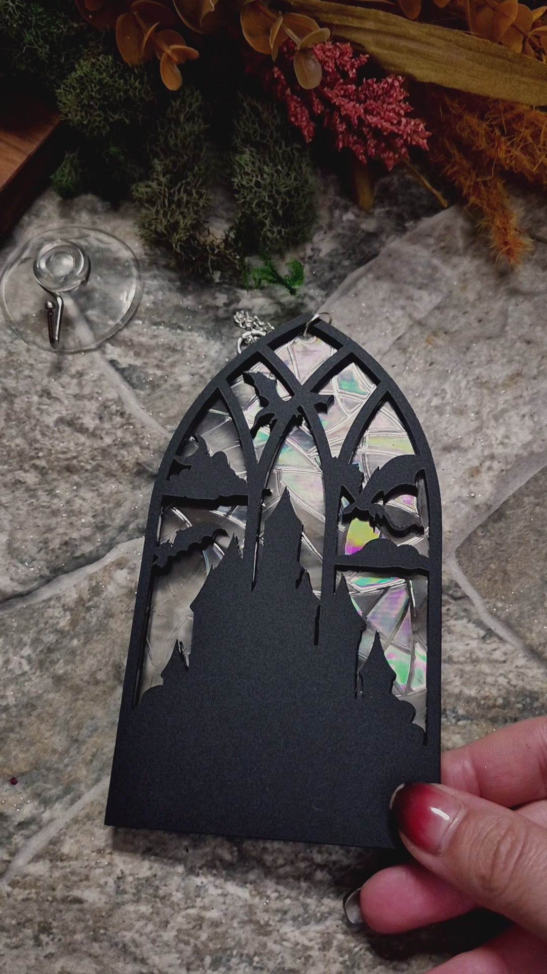 video of Gothic Dragon Window Suncatcher on a stone background surrounded by foliage 