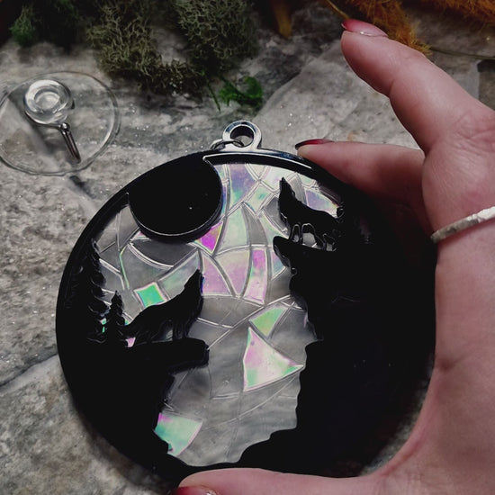 video of howl at the moon suncatcher on a stone background surrounded by foliage 

