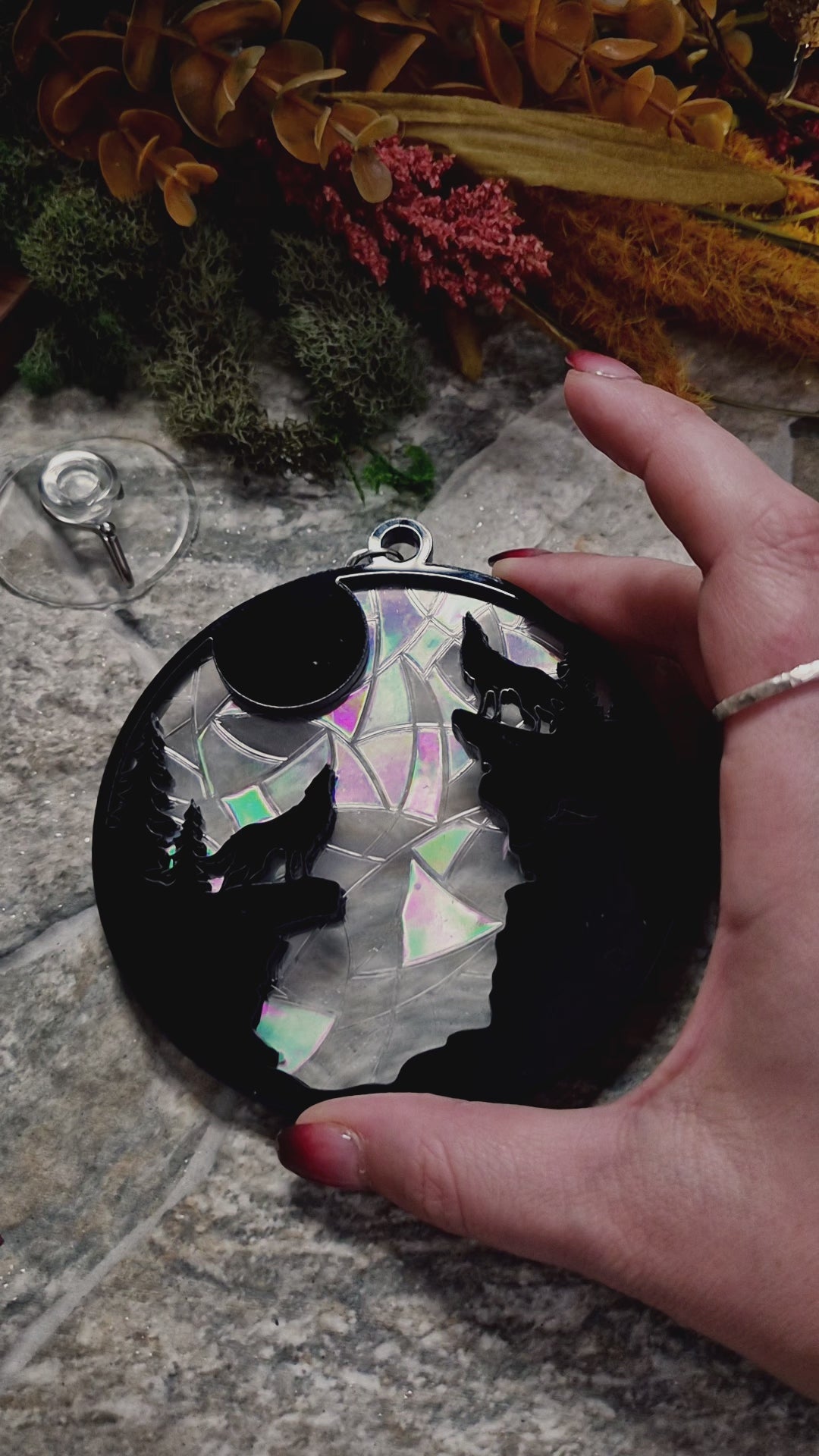 video of howl at the moon suncatcher on a stone background surrounded by foliage 
