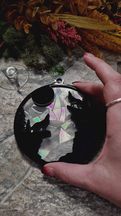 video of howl at the moon suncatcher on a stone background surrounded by foliage 
