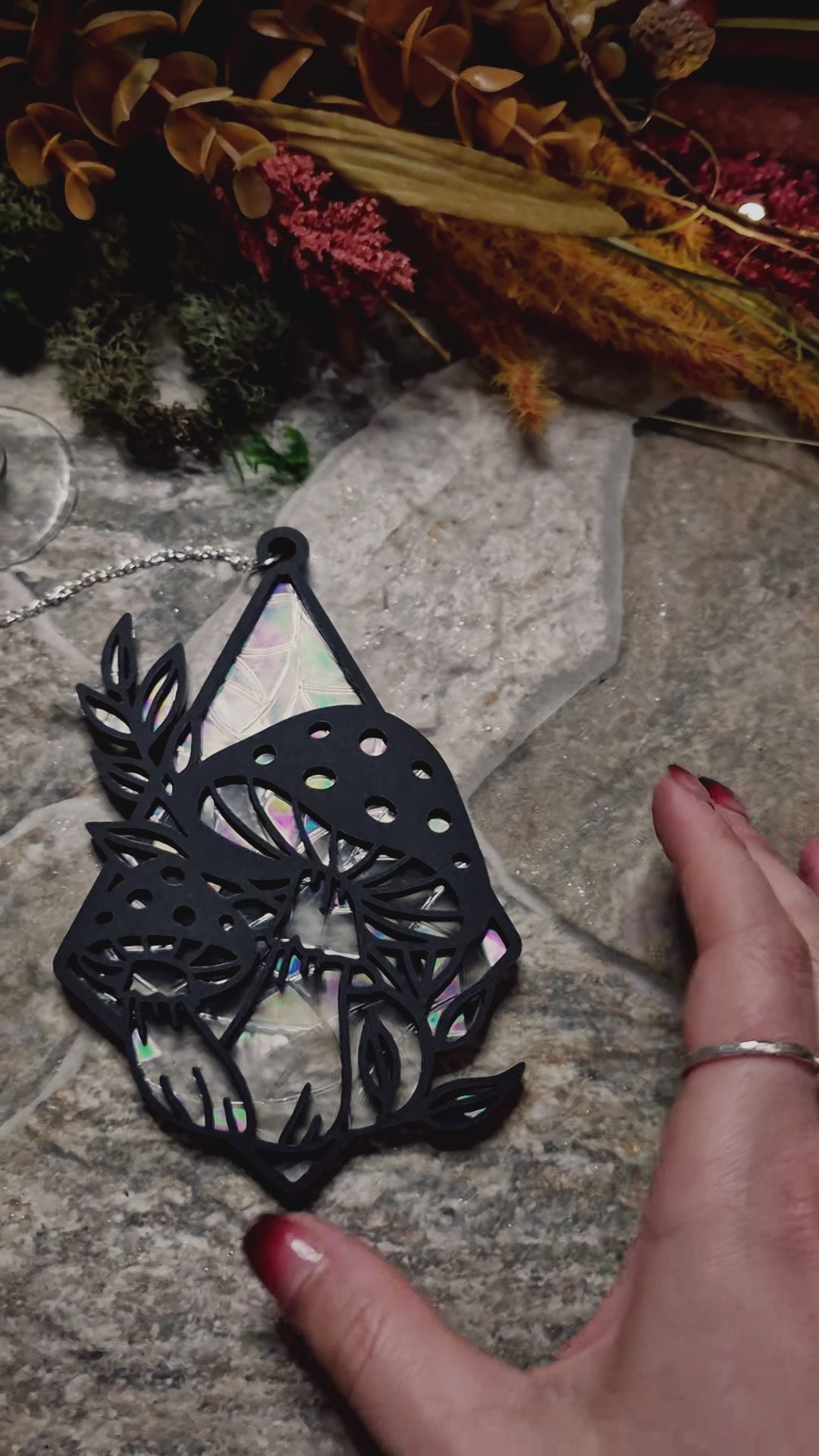video of mushroom suncatcher on a stone background surrounded by foliage 
