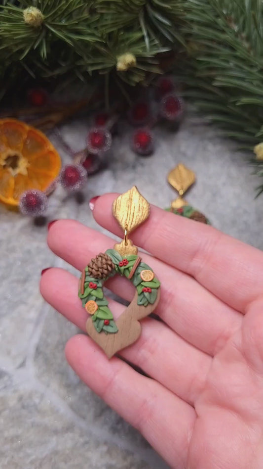 video close up of Yuletide Ornament Earring on a stone background surrounded by foliage. 