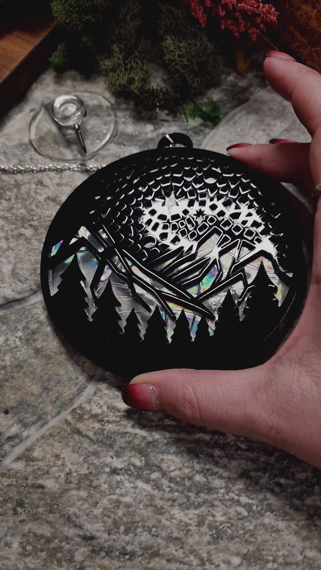 video of starry mountain  suncatcher on a stone background surrounded by foliage 

