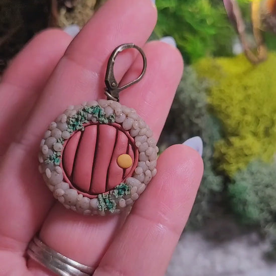 video close up of fairy door earrings on wood and stone background surrounded by moss