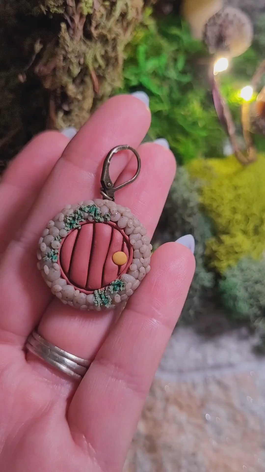 video close up of fairy door earrings on wood and stone background surrounded by moss