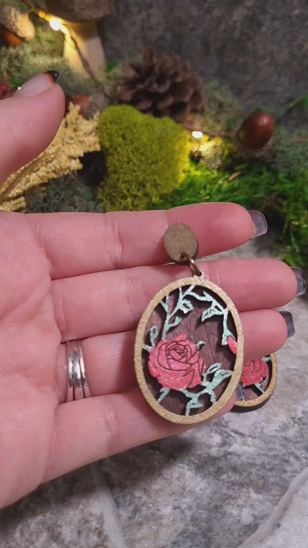 video close up Spring Court Earrings on a stone background surrounded by foliage