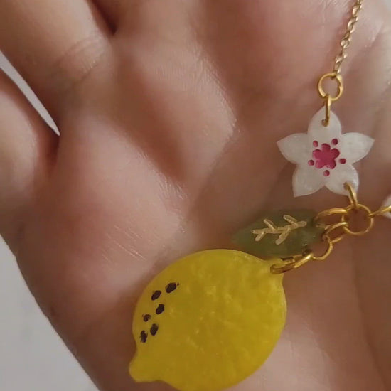 Closeup of resin lemon blossom necklace in palm of hand to show size and color detail.