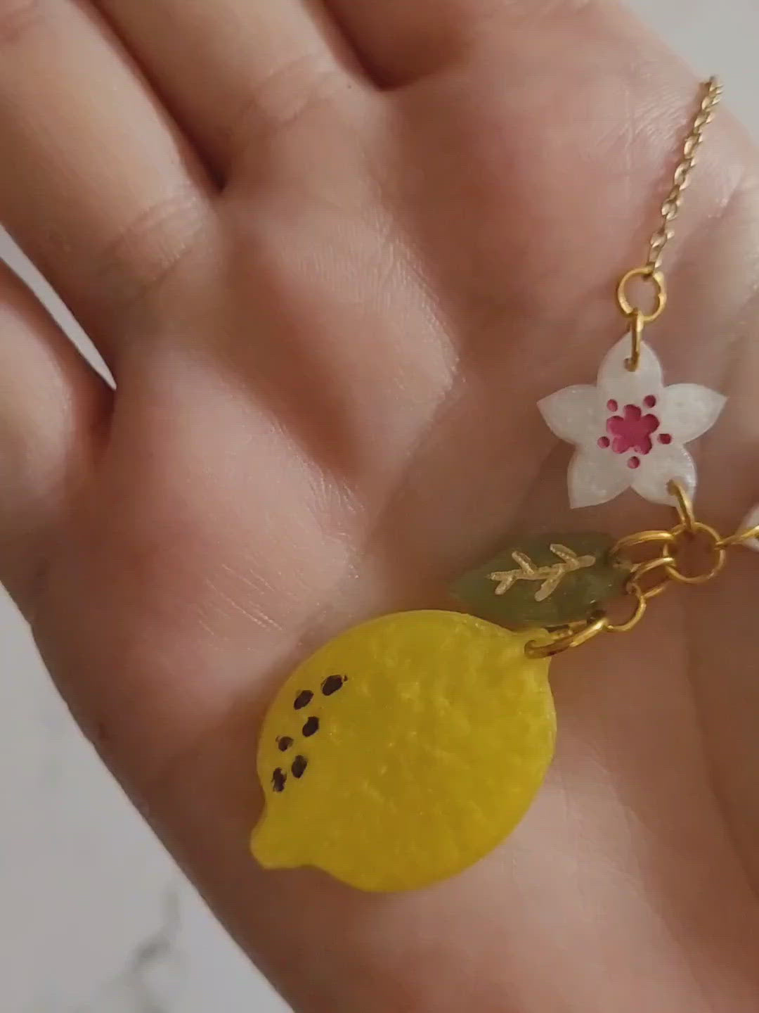 Closeup of resin lemon blossom necklace in palm of hand to show size and color detail.