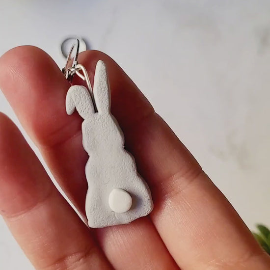 video close up of grey bunny earrings. 