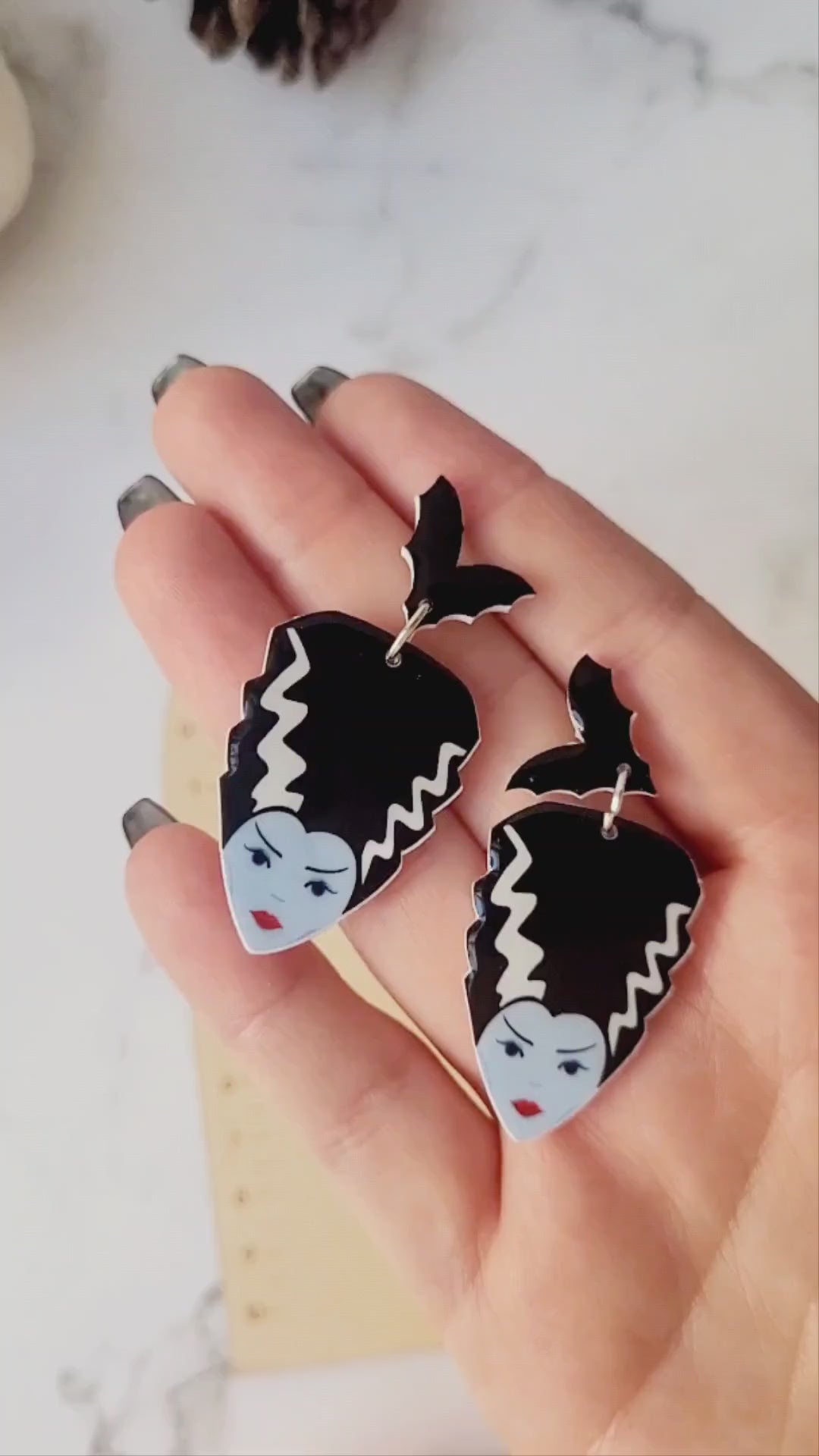 video close up of Bride of Frankenstein earrings on a marble background. 