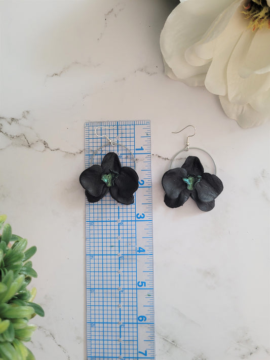 Black and metallic green polymer clay earrings in the shape of an orchid. 