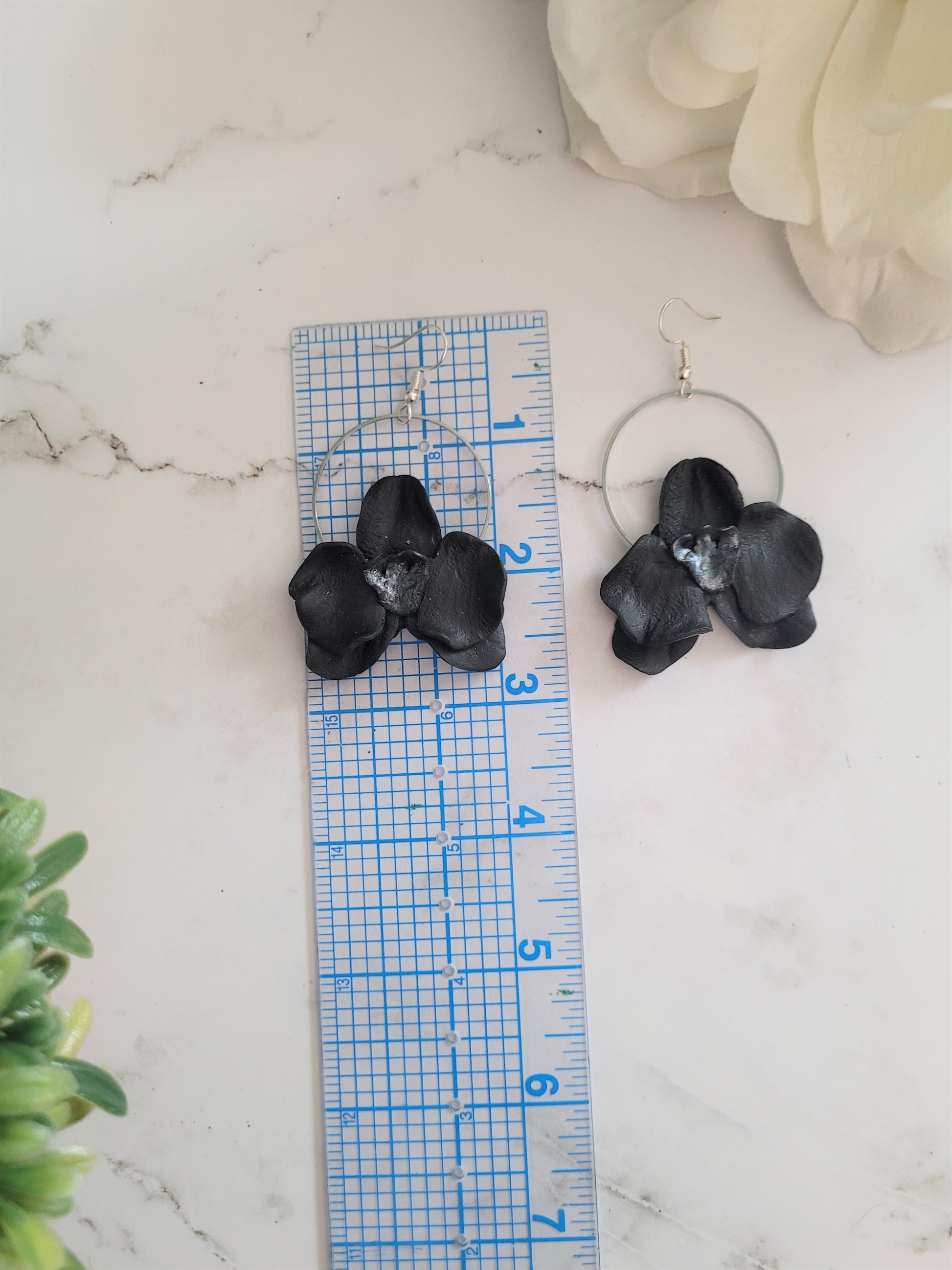 Black and metallic grey polymer clay earrings in the shape of an orchid. 