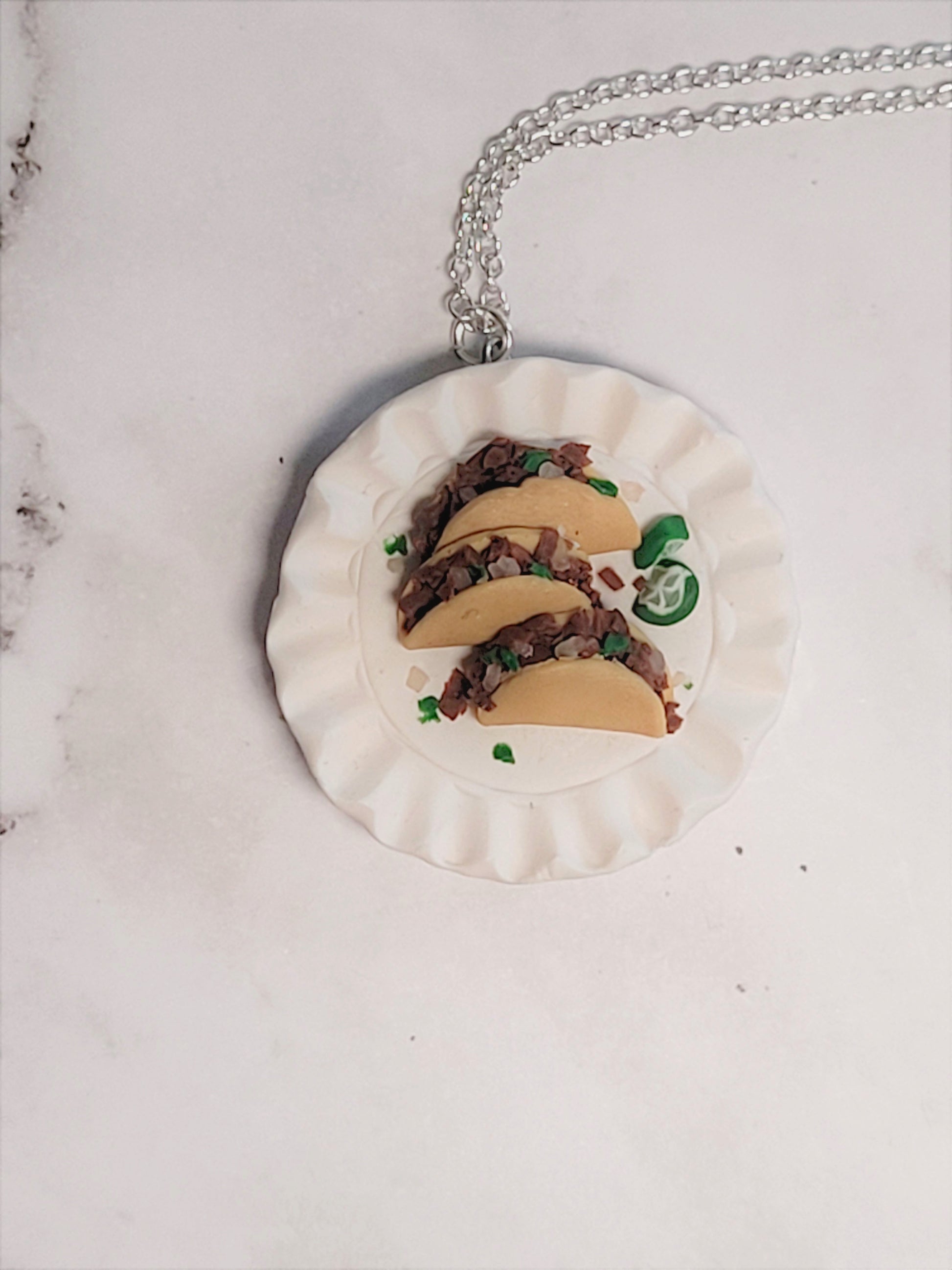 Close up of Polymer clay necklace with a plate, street tacos, and lime wedges.