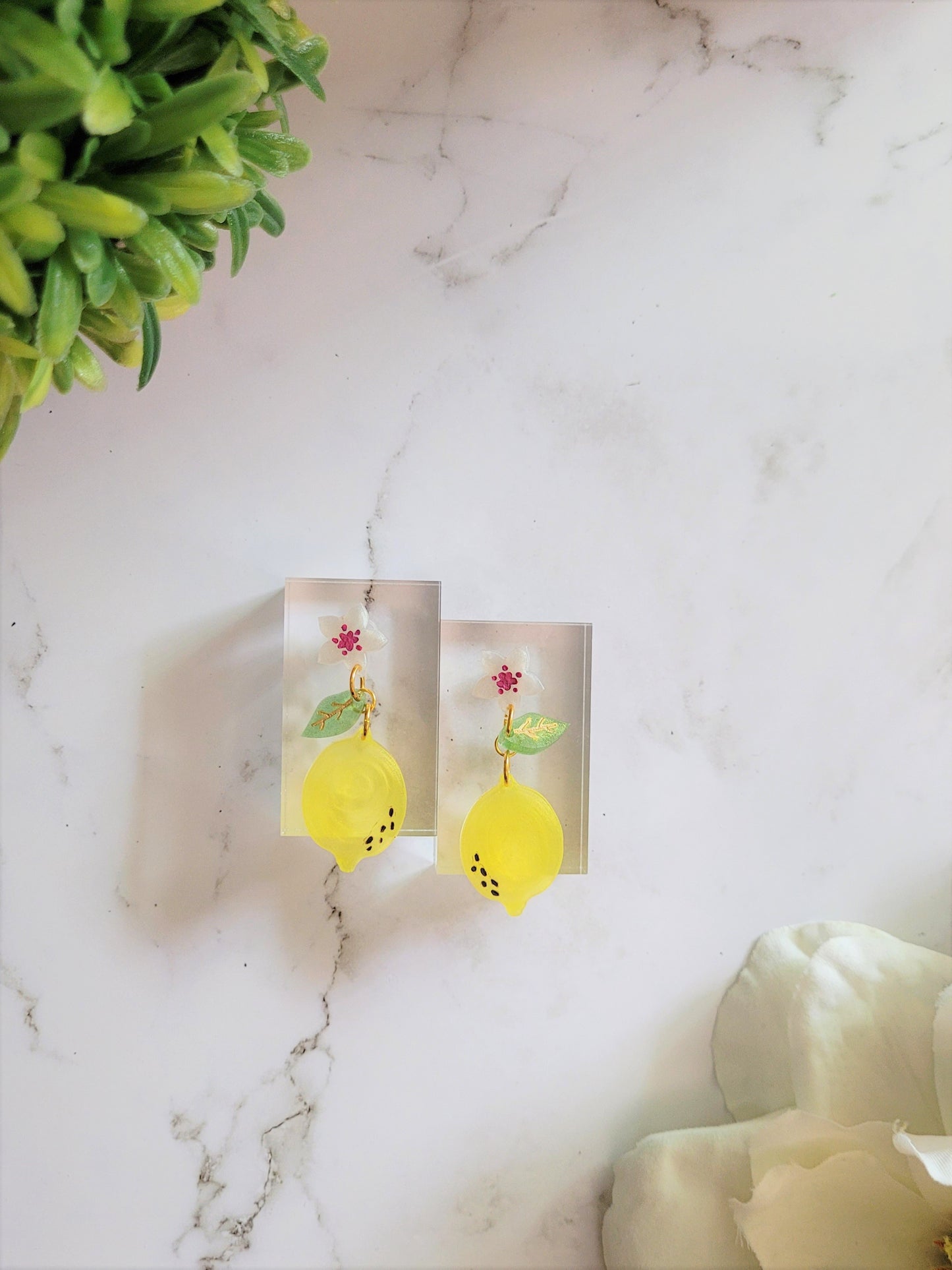 Resin earrings of lemon blossom, with fruit and leaf dangling below.