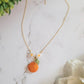 Necklace of orange blossom, leaf, and fruit dangling from dainty gold chain. 