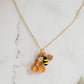 Closeup of honeycomb shaped resin necklace with bee charm on a white background.