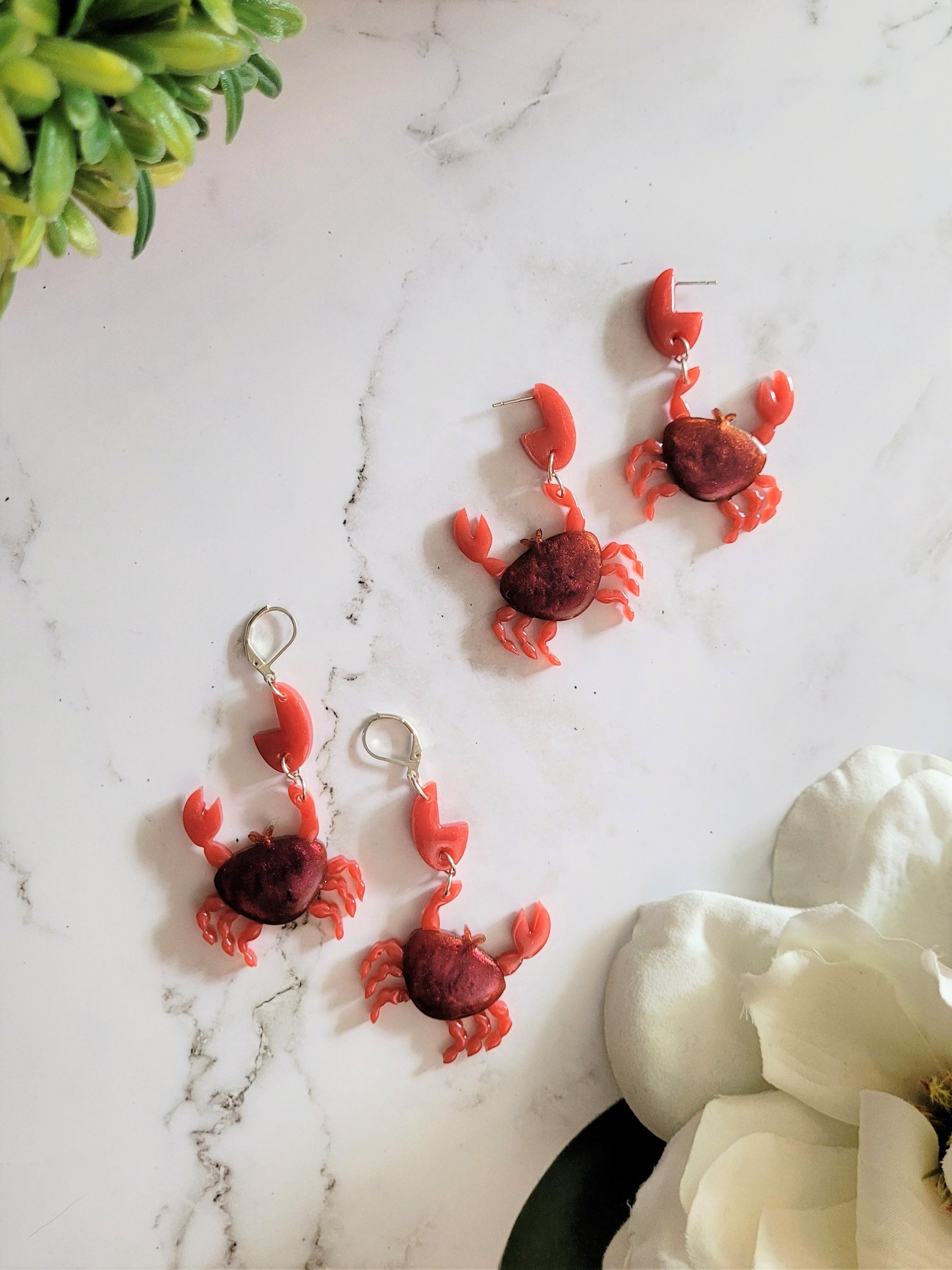 resin earrings in the shape of a red crab with metallic accents. 