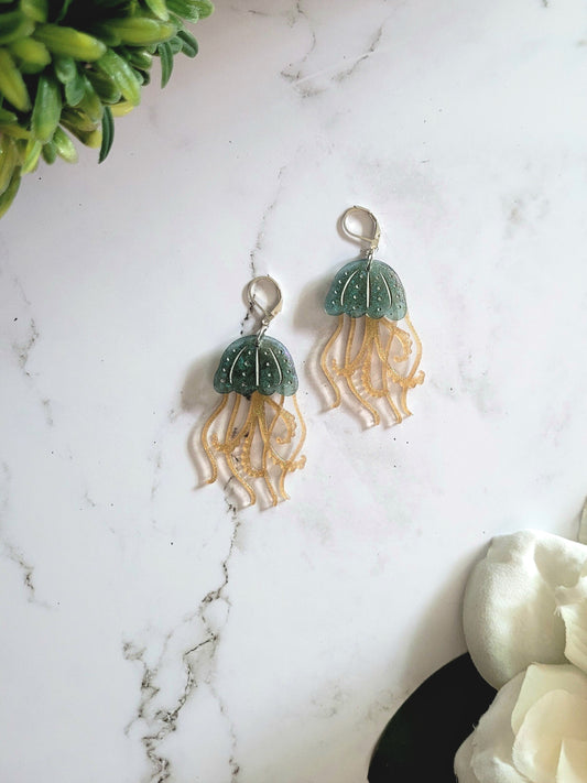 Resin earrings in the shape of a blue and gold jelly fish with metallic accents. 