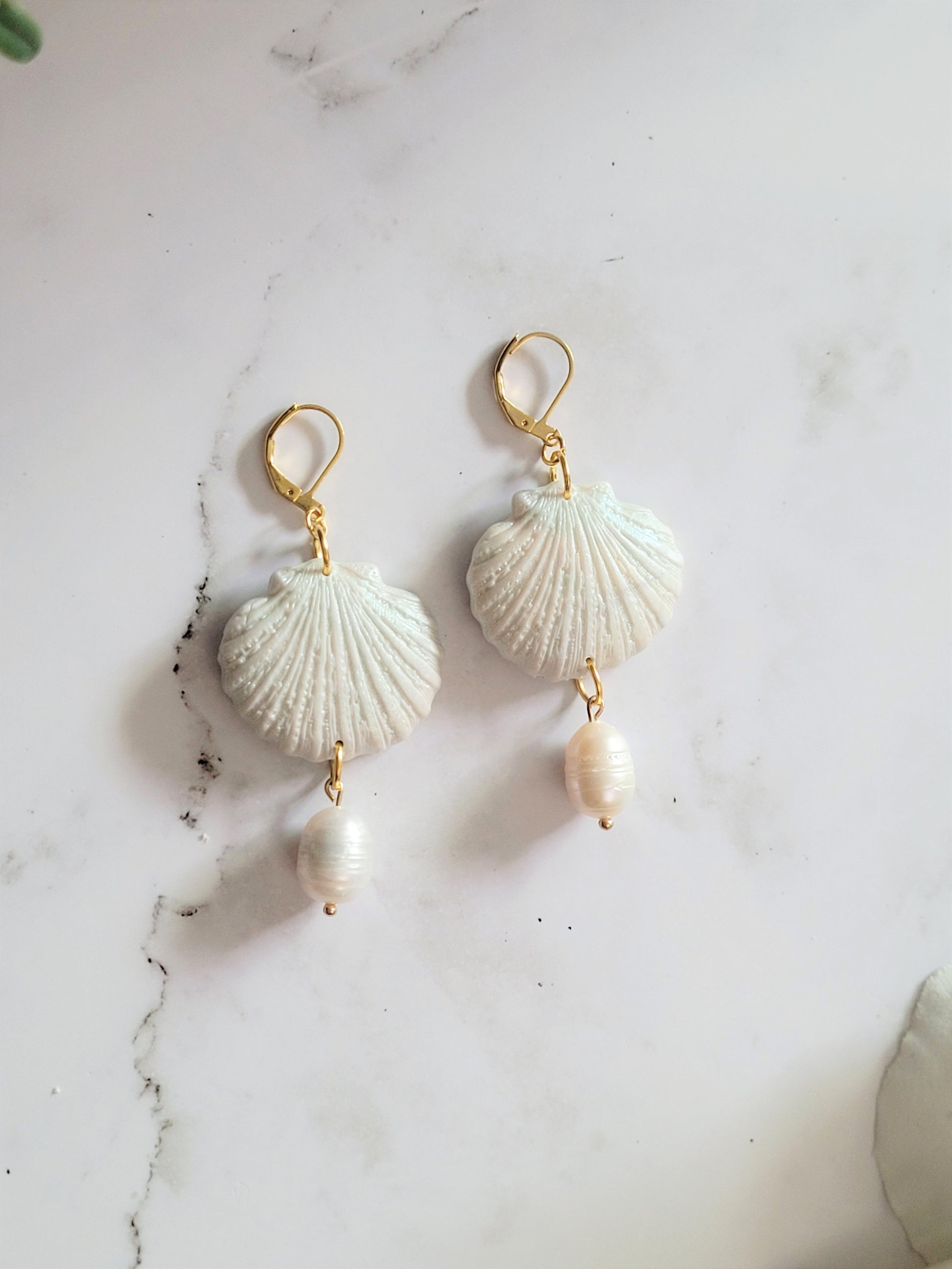 Closeup of scallop shell shaped polymer clay Earrings on a white background. Earrings are made of pearlescent clay.