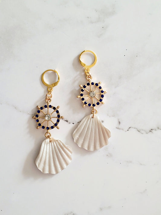 Close up of earrings with gold helm charm and polymer clay sea shell