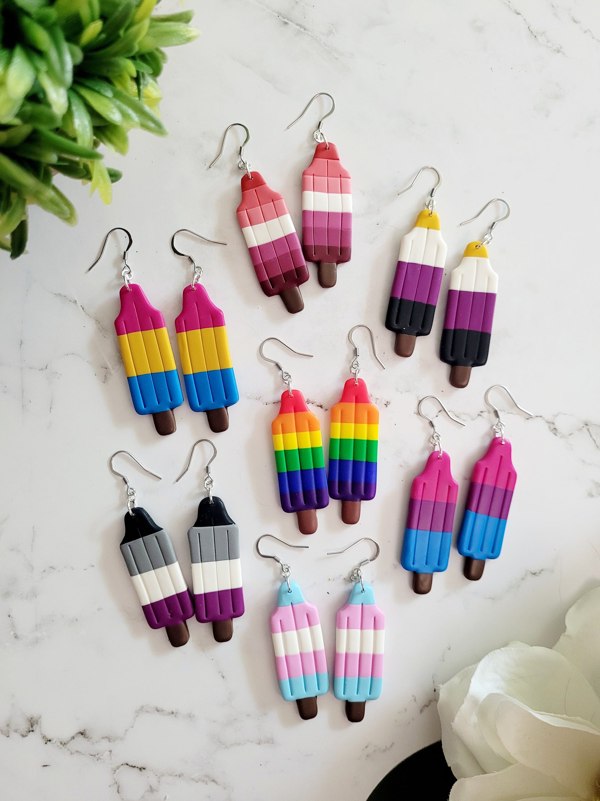 7 different Pride Flags in the shape of a Bomb Pop Popsicle Earrings.