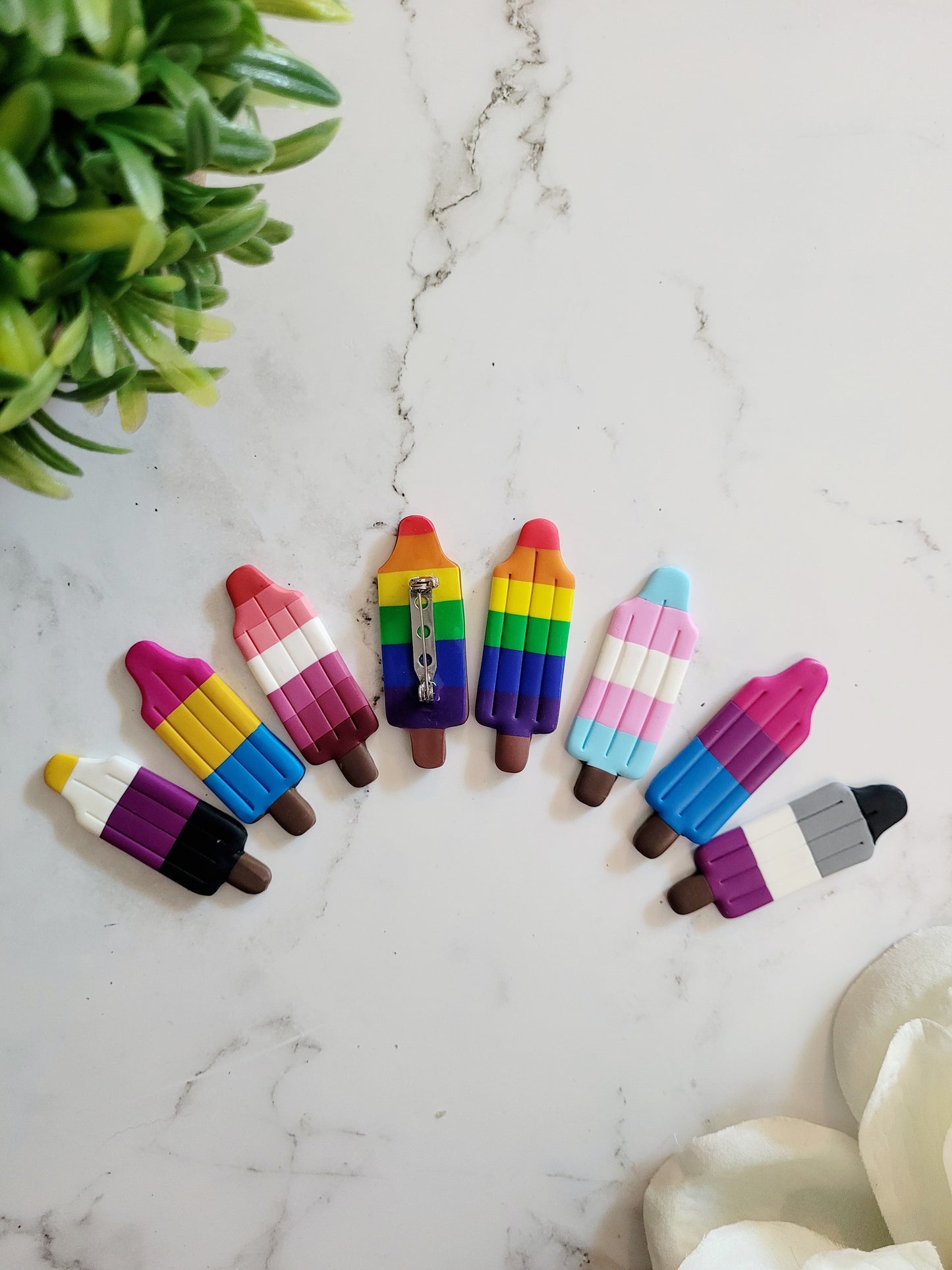 7 different Pride Flags in the shape of a Bomb Pop Popsicle