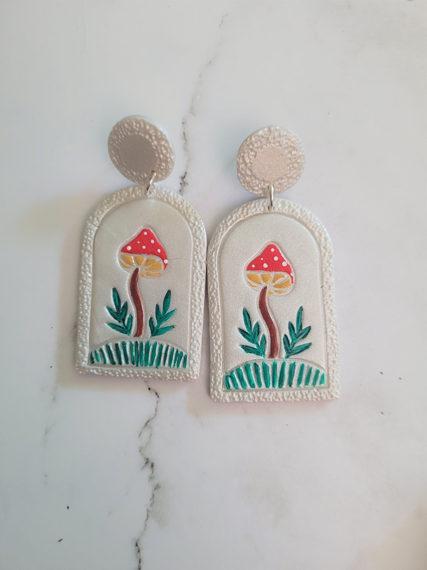 Closeup of Pearl earrings with painted mushroom