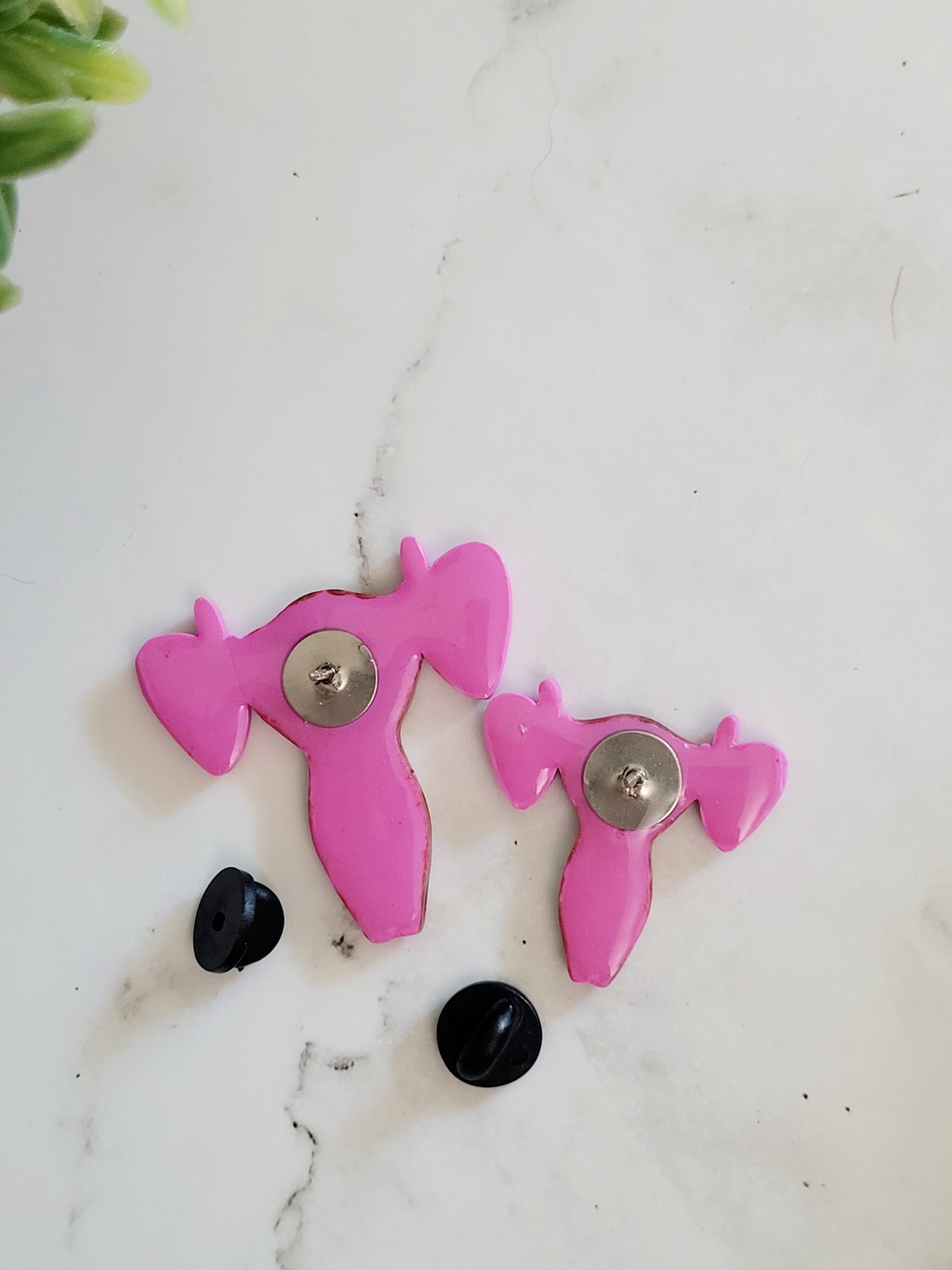 back of Pink uterus pin with middle finger fallopian tubes.