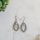 Closeup of small silver Vulva shaped earrings with pearl bead