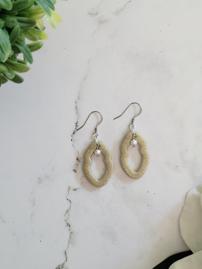 Closeup of small champagne Vulva shaped earrings with pearl bead