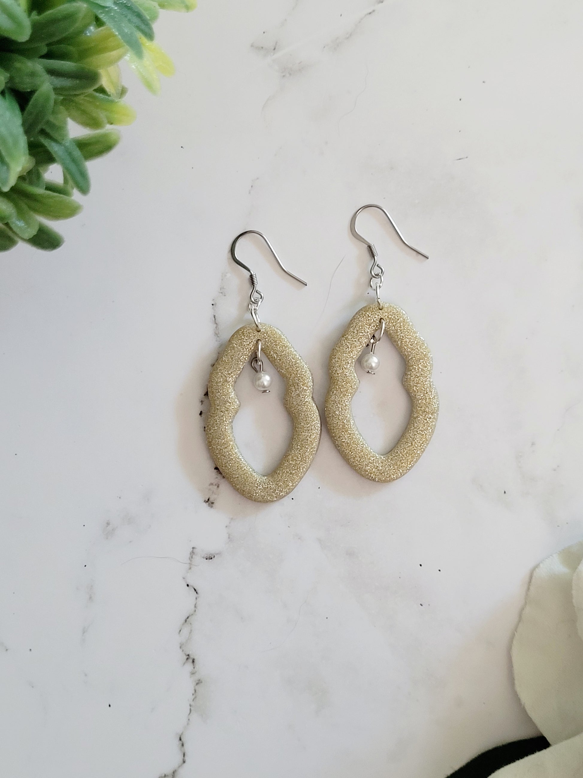 Closeup of large champagne Vulva shaped earrings with pearl bead