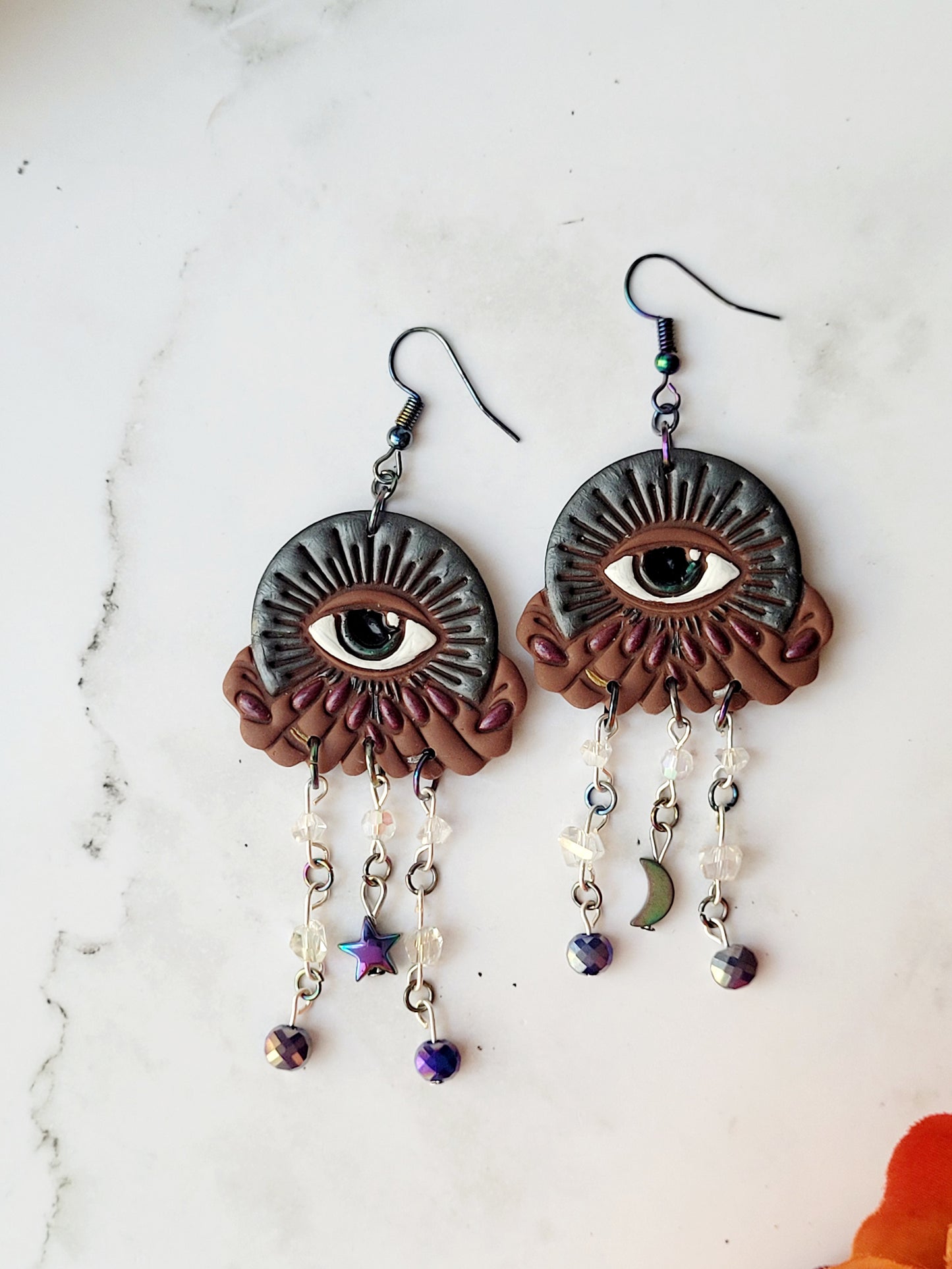 close up of All seeing eye earrings in dark skin tones