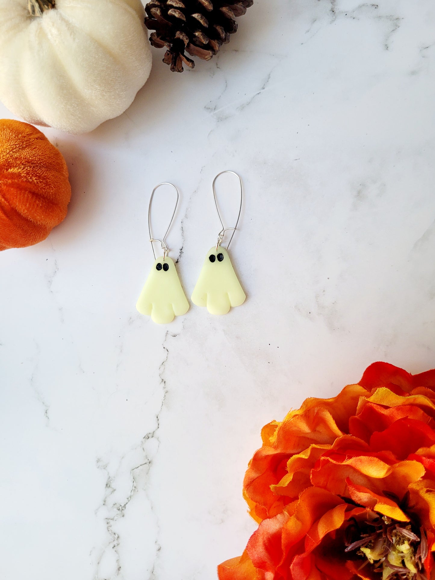 glow in the dark ghost earrings on a white marble background.